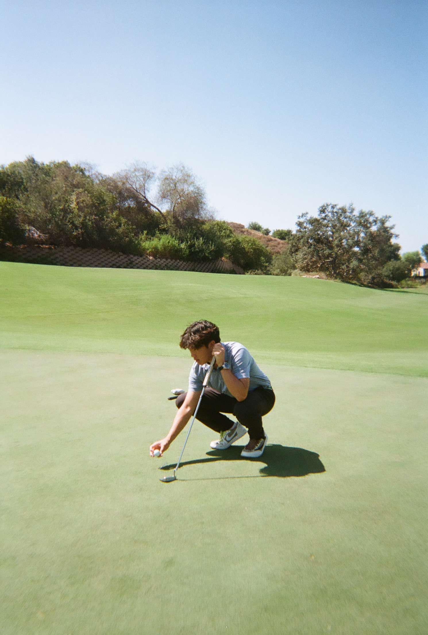 Film photo of Brandon marking his ball on the green