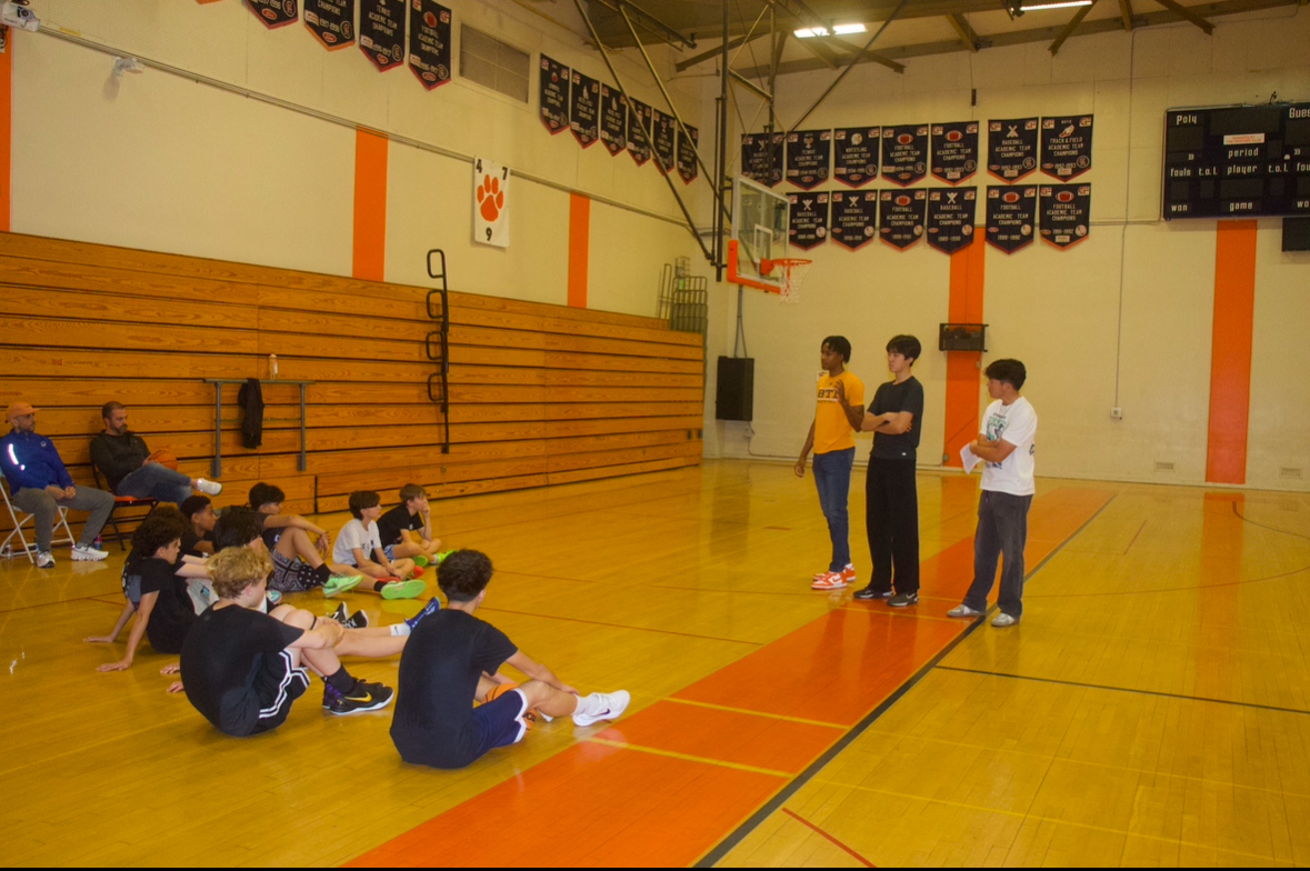 Brandon and Champion Minds volunteers speaking to young athletes in a gymnasium