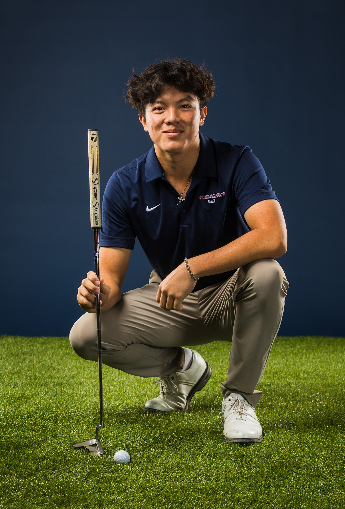 Studio portrait of Brandon Yang kneeling with his putter